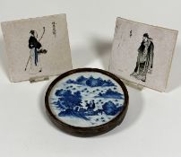 A pair of Japanese tiles depicting a figure with basket of flowers and a figure dressed in