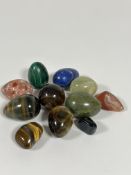 A collection of polished egg shaped hardstone including two tigers eye eggs, a circular tigers eye