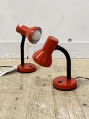 A pair of articulated desk lamps, finished in red