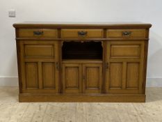 An Edwardian oak sideboard, with three drawers, open shelf and three panelled cupboards, on a