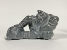 A carved hard stone sculpture modeled as a recumbent Intuit fisherman L29cm