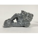 A carved hard stone sculpture modeled as a recumbent Intuit fisherman L29cm