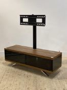 A contemporary TV stand, the walnut veneered base with two smoked glass cupboard doors, raised on