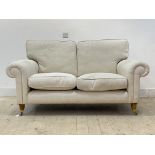 A traditional two seat sofa, upholstered in natural herringbone linen, raised on turned front