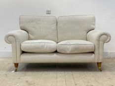 A traditional two seat sofa, upholstered in natural herringbone linen, raised on turned front