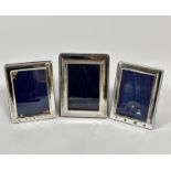 A pair of silver rectangular cushion framed photograph frames, the lined interiors of blue plush,