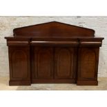 A mid 19th century mahogany side cabinet, with arched ledge back over inverted break front, three