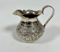 An Eastern white metal baluster jug with scalloped top and C scroll handle to side with chased