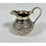 An Eastern white metal baluster jug with scalloped top and C scroll handle to side with chased