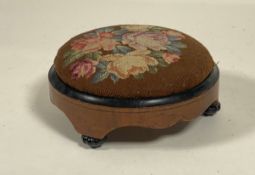 A mid 19th century walnut and pine circular footstool, the embroidered top worked in a floral design