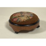 A mid 19th century walnut and pine circular footstool, the embroidered top worked in a floral design