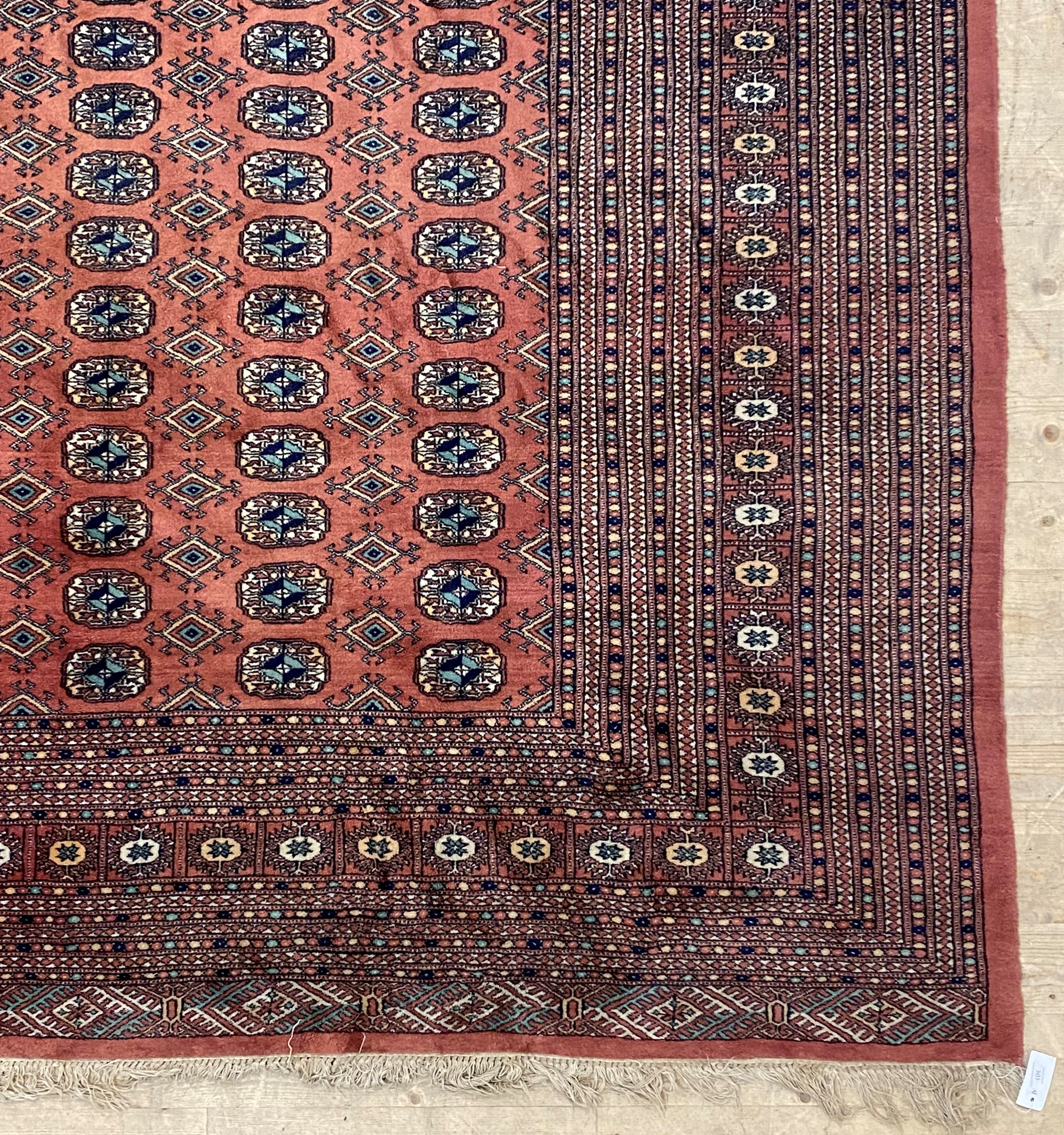 An Afghan bokhara carpet, the red field with multiple rows of guls within a guarded border 379cm x