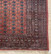 An Afghan bokhara carpet, the red field with multiple rows of guls within a guarded border 379cm x