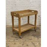 A beech two tier side table moving on castors, H81cm, W86cm, D46cm