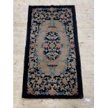 A Chinese rug, the black field with floral design, 176cm x 74cm