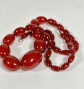 A 1920s style amber oval graduated bead necklace, missing part of clasp, (L 30cm) of carnelian