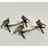 A pair of white metal branch knife rests with dove figures with pair of bird terminal figures on