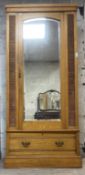 An Edwardian ash single wardrobe, the mirrored door enclosing interior fitted for hanging, drawer to