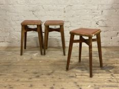 A set of three 1950's stained beech bar stools, vinyl upholstered seats raised on splayed