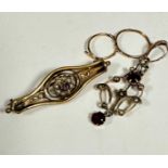 An Edwardian yellow metal open work pendant set garnet and seed pearls in C scroll and floral