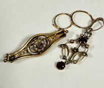 An Edwardian yellow metal open work pendant set garnet and seed pearls in C scroll and floral
