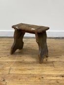 A rustic 19th century pine stool of jointed construction, standing on splayed and shaped panel end