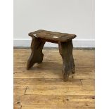 A rustic 19th century pine stool of jointed construction, standing on splayed and shaped panel end