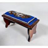 An Edwardian rosewood travelling footrest with beadwork panelled top, with stylised roses and