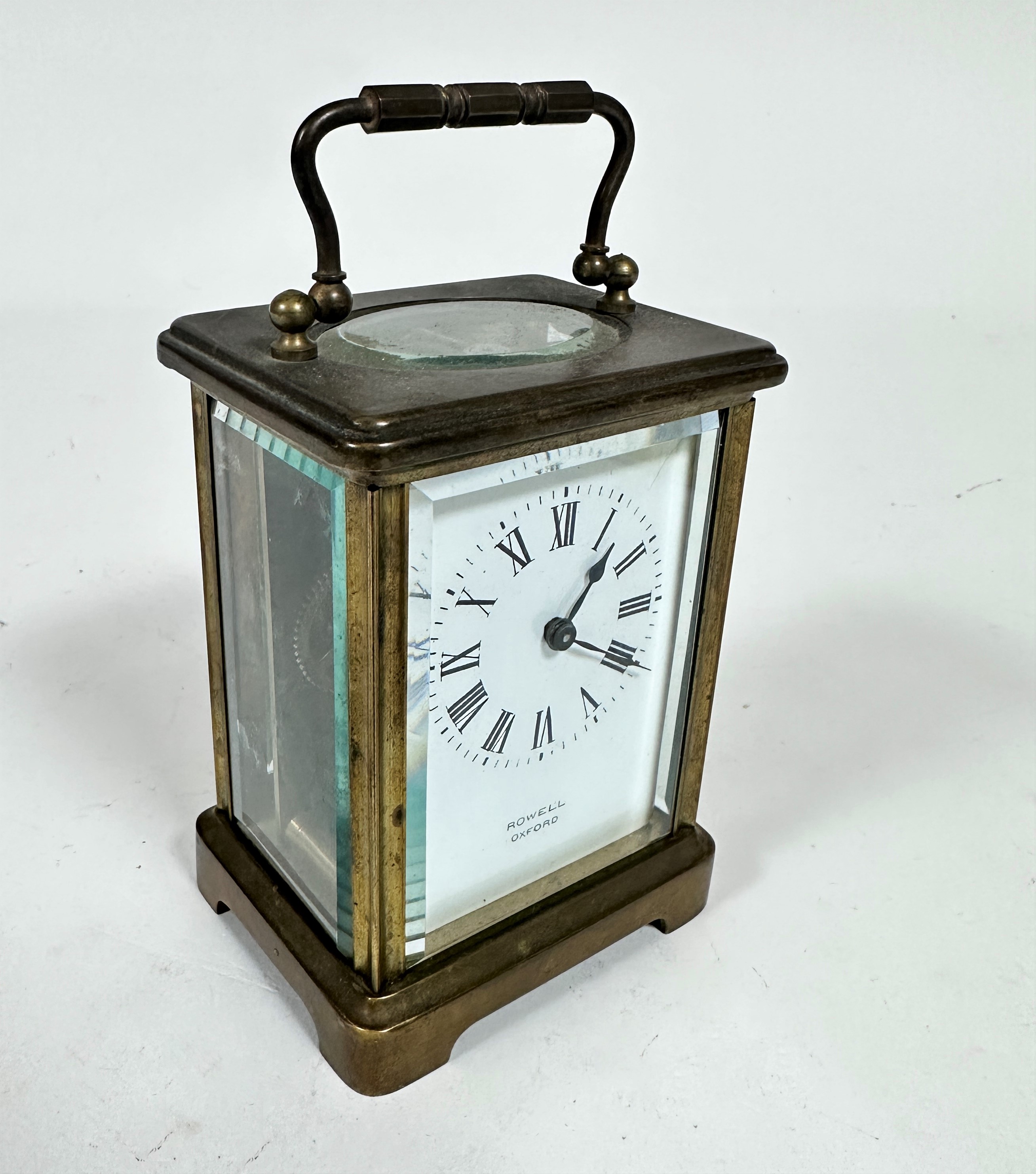 A French brass four glass carriage clock with enamelled dial, retailed by Rowell of Oxford, with