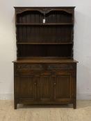 A 1930's oak dresser, two height plate rack over base with two drawers and cupboard, raised on stile