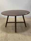 Ercol, a beech and elm extending dining table, the circular top on four splayed supports united by a