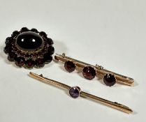 A 9ct gold knife edge bar brooch set three circular graduated garnets, the centre stone approx .5ct,