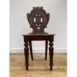 A Victorian mahogany hall chair, the back of scrolled shaped form centred by a vacant cartouche,