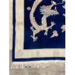 A Chinese washed wool ground rug, the blue field with dragon motif within an ivory border 300cm x