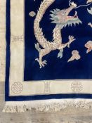 A Chinese washed wool ground rug, the blue field with dragon motif within an ivory border 300cm x