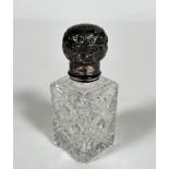 An Edwardian silver mounted crystal slice cut perfume bottle with lift up top enclosing faceted