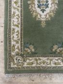 An Indian washed wool rug, the green ground with ivory medallion and bordered 195cm x 97cm