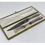 A pair of Dutch white metal thistle decorated handled carving knife and fork, in original