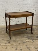 A mid century teak metamorphic drinks table, the folding top over under tier, moving on castors,