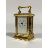 A Brass carriage time piece clock, the case with shaped swing handle over bevelled glass to each