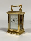 A Brass carriage time piece clock, the case with shaped swing handle over bevelled glass to each