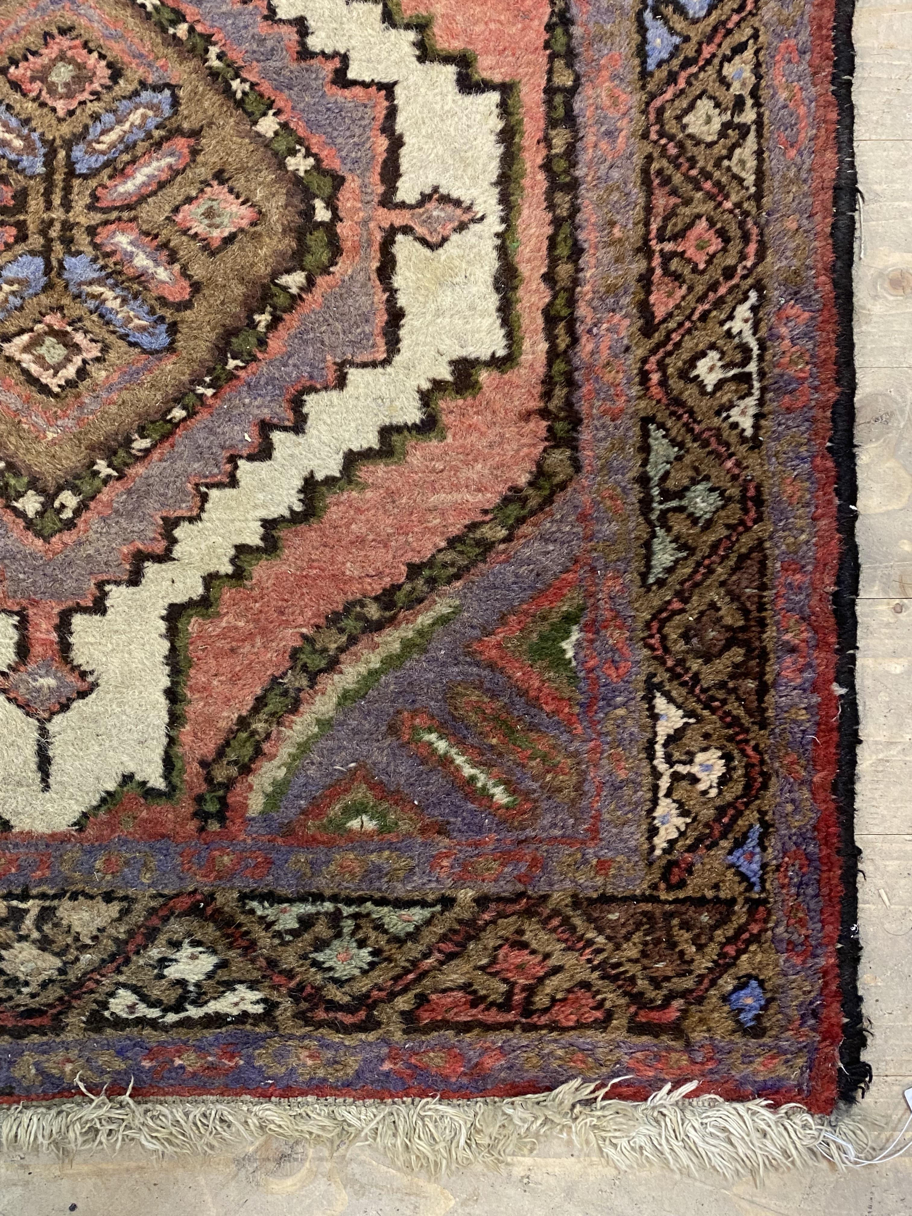 A Persian Hamadan hand knotted runner rug, with pole medallion on red field enclosed by a border