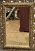 An Edwardian rectangular gilt wall mirror with floral and scroll mount, (mirror 44cm x 26cm, frame