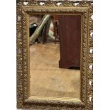 An Edwardian rectangular gilt wall mirror with floral and scroll mount, (mirror 44cm x 26cm, frame