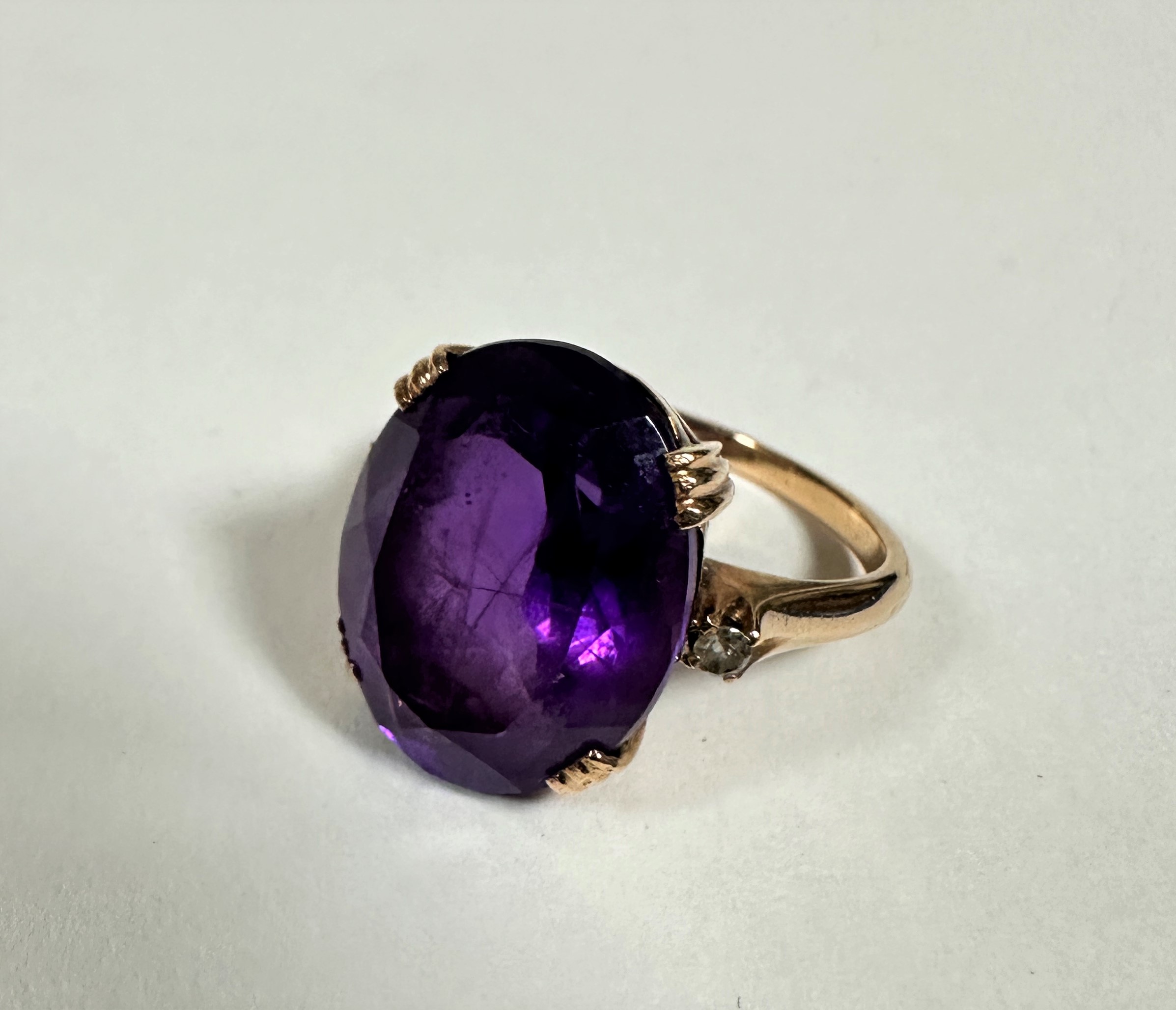 An 18ct gold dress ring set oval faceted amethyst with diamond point set shoulders, mounted in
