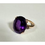 An 18ct gold dress ring set oval faceted amethyst with diamond point set shoulders, mounted in