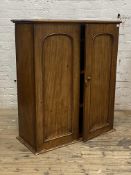 A Victorian mahogany cabinet, twin arched panelled doors enclosing three shelves (formerly top