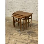 A mid century teak nest of three tables, cross banded tops raised on turned supports, H50cm,