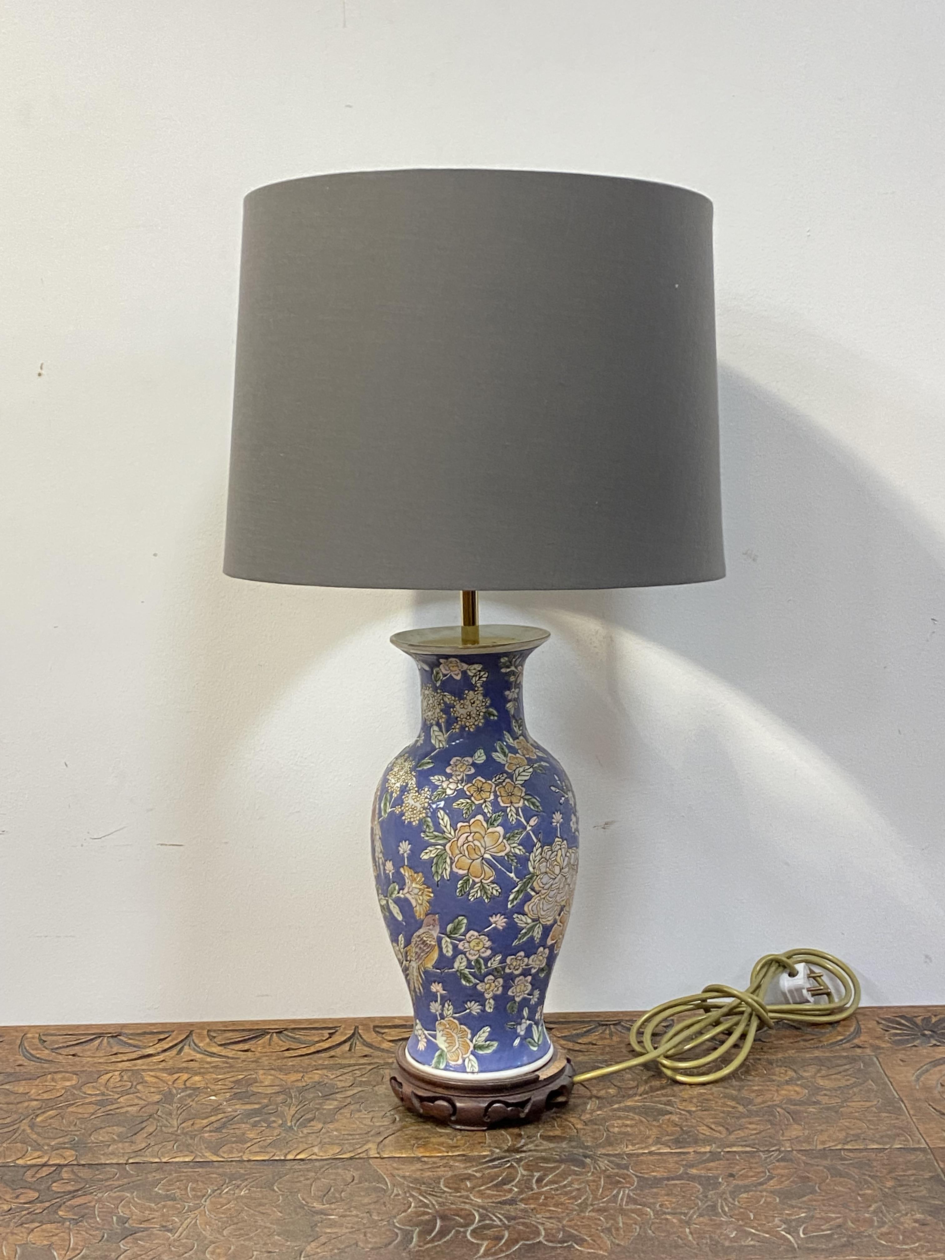 A Chinese style ceramic baluster lamp, enamelled with lotus heads and birds, on a hardwood base