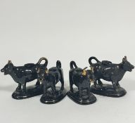A group of four 19thc pottery black and gilt decorated cow creamers, no signs of repairs to tails,